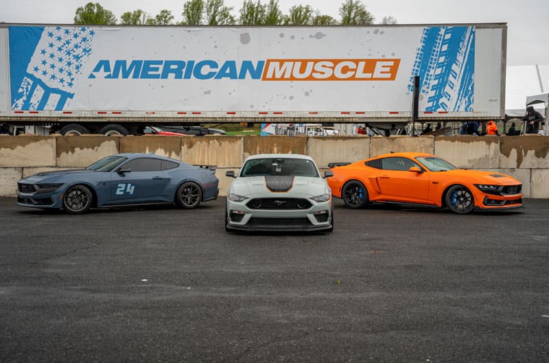blue white and orange Mustangs in front of American Muscle sign